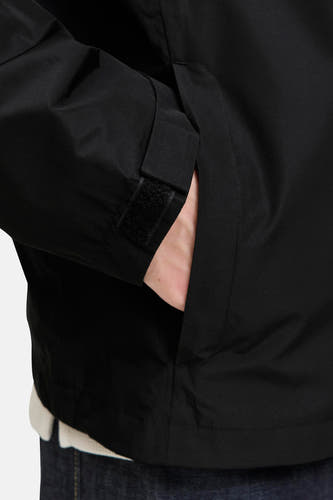 Manteau court noir d'ORIGINALS BY JACK & JONES, avec une main dans la poche et un col ajustable.