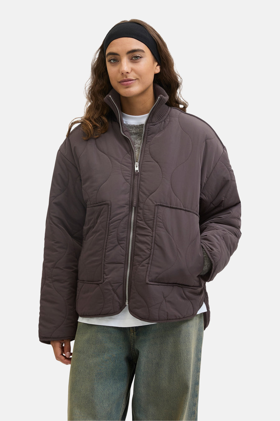 Manteau court brun de JJXX, avec un motif de visière effiloché et une fermeture éclair argentée, porté sur un pull gris et des jeans bleus.