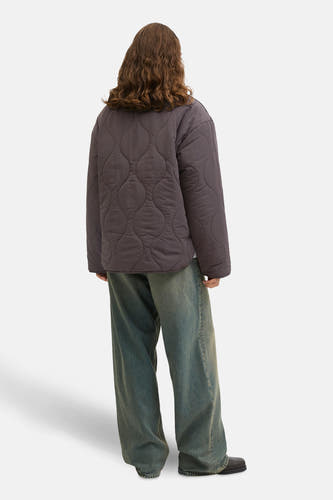 Manteau court brun de JJXX, avec un motif en duvet, porté avec des jeans larges et des chaussures noires.