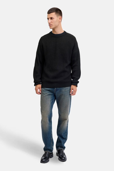Pull-over noir avec col rond de PREMIUM by JACK & JONES, porté avec des jeans bleus et des loafers noirs.