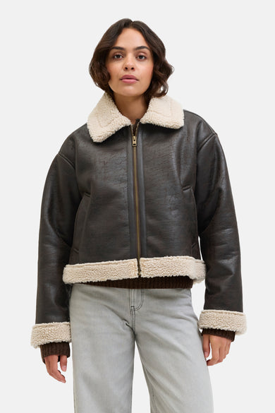 Manteau court brun de JJXX, avec des manches longues, un col blanc et des jeans gris.