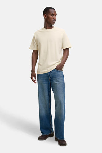 T-shirt beige à manches courtes de CORE BY JACK & JONES, porté avec des jeans larges et des chaussures marrons.