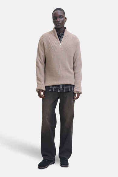 Pull-over beige de PREMIUM par JACK & JONES, porté sur une chemise à carreaux et des jeans larges.
