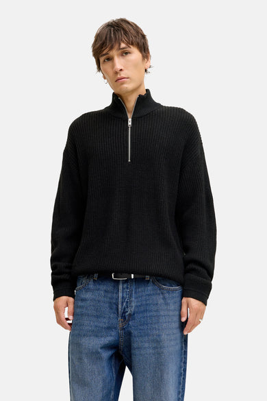 Sweat-shirt noir PREMIUM par JACK & JONES, avec une fermeture à glissière courte et porté avec une ceinture et un jean.