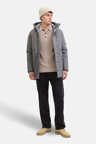 Gilet beige à col V de PREMIUM par JACK & JONES, associé à un manteau gris, des pantalons noirs et des chaussures beige.