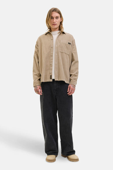 Chemise brune à longues manches de PREMIUM BLUE par JACK & JONES, avec col boutonné et poche poitrine, portée sur une chemise crème.