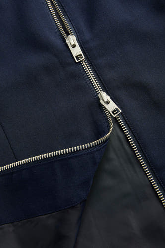 Blouse bleue de JJXX, avec une fermeture éclair argentée et une texture lisse et ajustée, partiellement ouverte.