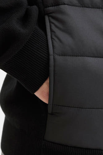 Gilet noir de CORE BY JACK & JONES, avec une main dans la poche et un motif bouclé.