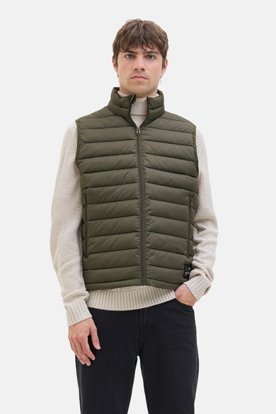 Gilet vert de JJREBEL, porté sur un pull tricoté et associé à des jeans noirs.