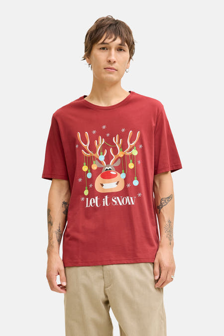 T-shirt rouge à manches courtes d'ORIGINALS BY JACK & JONES, avec imprimé de Noël, porté sous un manteau de denim bleu marine et un pantalon beige.