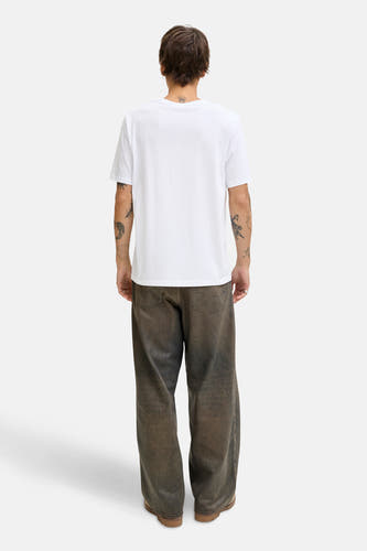 T-shirt blanc à manches courtes d'ORIGINALS BY JACK & JONES, avec des tatouages visibles et un pantalon brun large.