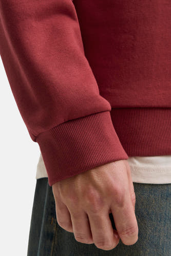 Pull-over rouge d'ORIGINALS BY JACK & JONES, avec des manches longues et des bordures côtelées, porté avec un T-shirt blanc et un jean.