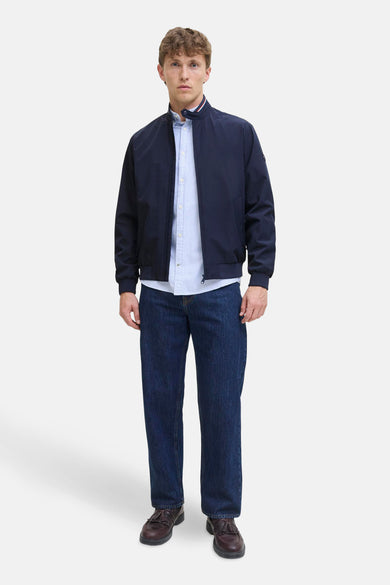 Manteau court bleu d'ORIGINALS BY JACK & JONES, porté sur un chemisier rayé avec des jeans foncés et des chaussures en cuir.