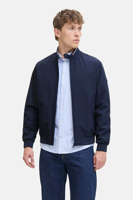 Manteau court bleu d'ORIGINALS BY JACK & JONES, avec fermeture éclair et porté sur un chemisier rayé et des jeans foncés.