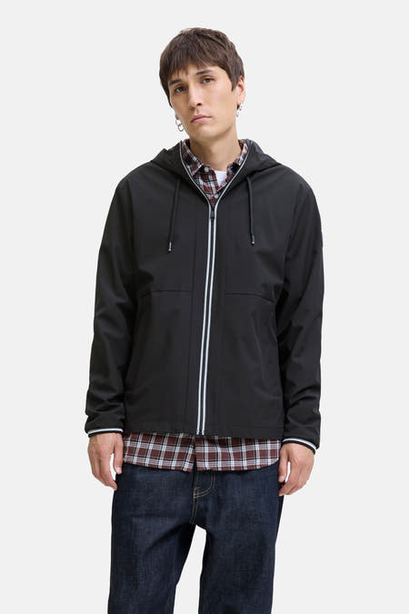 Manteau court noir d'ORIGINALS BY JACK & JONES, avec capuche, fermeture éclair avec des accents blancs et des jeans noirs.