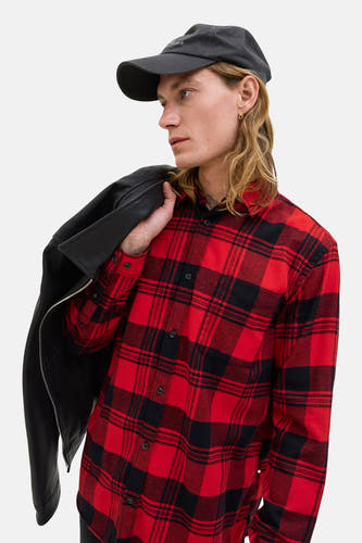 Chemise à carreaux rouge avec longues manches de PREMIUM BLUE par JACK & JONES, portée sur l'épaule avec une veste en cuir noire et un chapeau noir.