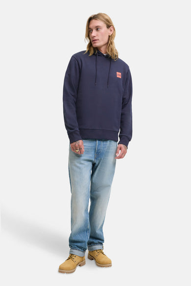 Pull-over bleu avec capuche d'ORIGINALS BY JACK & JONES, associé à des jeans bleus clairs et des bottes brunes.