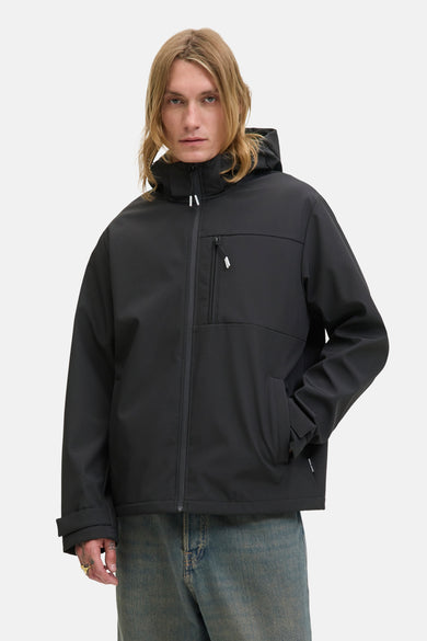 Manteau court noir de CORE par JACK & JONES, avec capuche et un modèle droit, porté avec un jean bleu.
