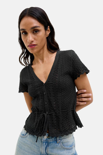 Sweat-shirt noir JJXX, à manches courtes, avec un col boutonné et une ceinture élastiquée, porté avec un jean.