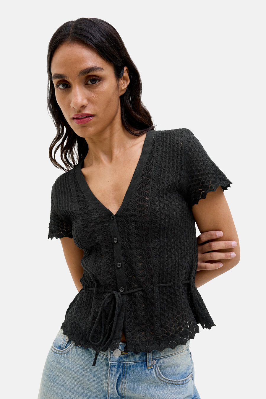 Sweat-shirt noir JJXX, à manches courtes, avec un col boutonné et une ceinture élastiquée, porté avec un jean.