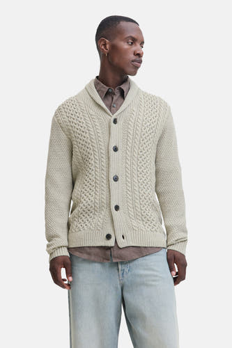 Gilet beige de PREMIUM BLUE par JACK & JONES, avec fermeture à boutons et porté sur un chemisier brun et des jeans larges.