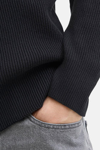 Gilet noir de CORE BY JACK & JONES, avec des côtes et une main visible dans un sac à pantalon gris.