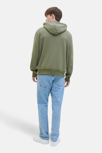 Pull-over vert de JJREBEL cap,JJ van van van g géé avec des jeans légers et des sneakers blanches.