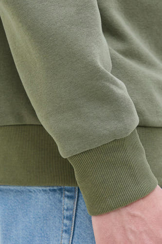 Sweater vert de JJREBEL, avec des manches côtelées et une partie d'un jean bleu visible.