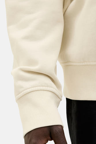 Sweater écru de ORIGINALS BY JACK & JONES, avec un bord côtelé et une représentation partielle d'une pantalon noir.