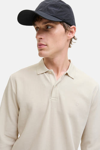 Gilet beige à col V de PREMIUM BLUE par JACK & JONES, avec une subtile texture et porté avec un chapeau noir.