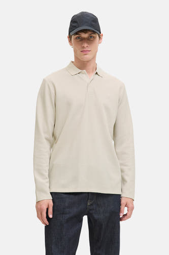 Pull beige à col V de PREMIUM BLUE par JACK & JONES, porté avec des jeans bleus foncés et un chapeau.
