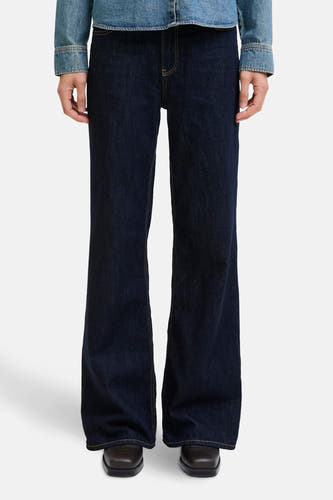 Jean flare bleu marine de JJXX avec des surpiqures jaunes, associé à une veste en denim sur un fond blanc.