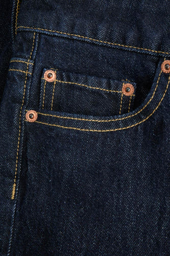 Jean en denim bleu marine de JJXX, avec des rivets cuivre et des surpiqures jaunes sur les poches.