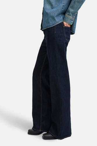 Jean flare bleu marine de JJXX, avec des surpiqures jaunes et une blouse en denim.