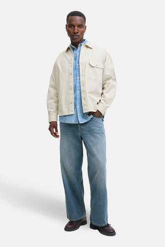 Chemise beige de PREMIUM BLUE par JACK & JONES, portée sur une chemise denim bleue et des jeans larges.