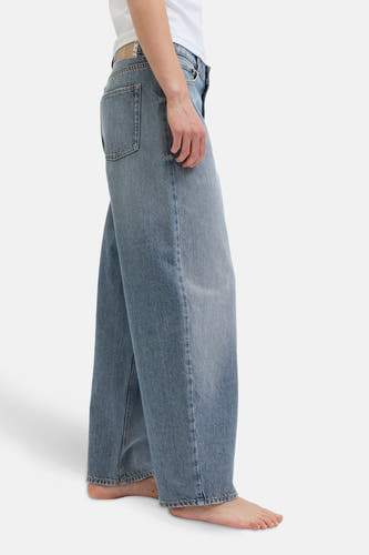Jean en denim bleu marine spécial fit de JJXX, avec une vue sur le côté et des larges pinces et des pieds nus.