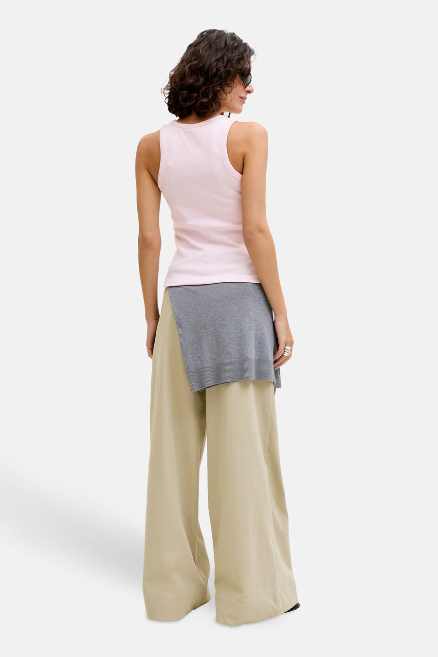 Haut côtelé rose de JJXX, porté avec un pull gris à la taille et un pantalon beige ample.