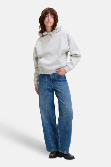 Pull-over gris avec capuche JJXX, doté d'une poche et associé à des jeans larges et des bottines noires.