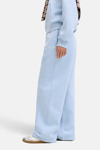 Pantalon de jogging bleu de JJXX Studio, avec jambes larges et chaussures argentées.