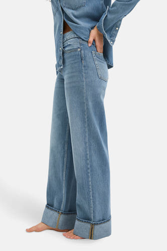 Jean décontracté en denim bleu de JJXX, avec des poches rabattues et une main dans la poche, montré sur le côté.