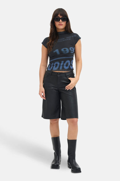 T-shirt bleu à manches courtes de JJXX, avec une impression bleue '1991' et porté avec un pantalon noir et des lunettes de soleil.