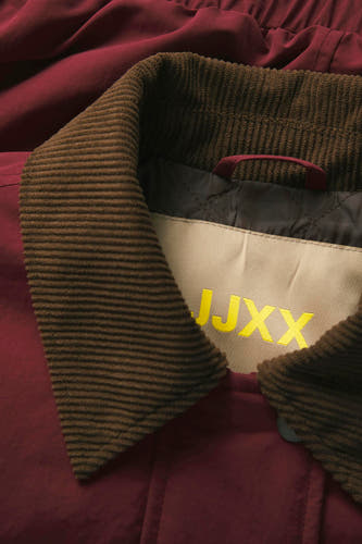 Veste rouge de JJXX, avec un col en fourrure brune et un logo brodé sur le dos.