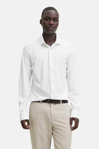 Chemise blanche à manches longues de PREMIUM by JACK & JONES, portée avec une ceinture marron et un pantalon kaki.