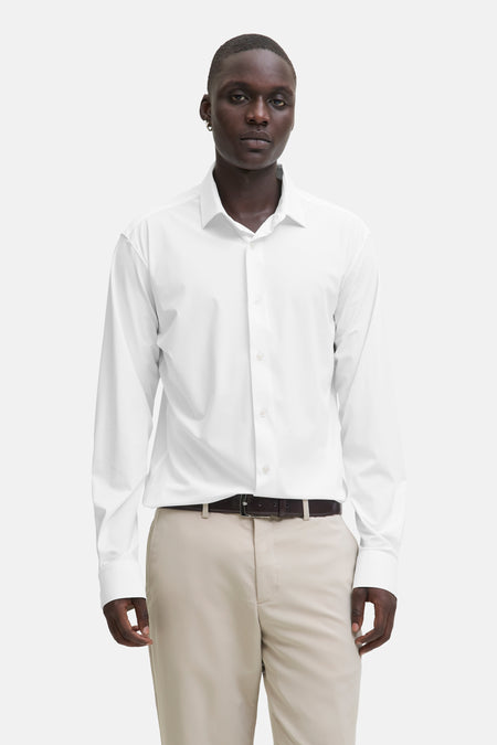 Chemise blanche à manches longues de PREMIUM by JACK & JONES, portée avec une ceinture marron et un pantalon kaki.