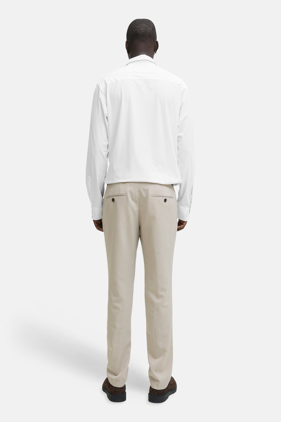 Chemise blanche à manches longues de PREMIUM by JACK & JONES, vue de dos, associée à un pantalon beige et des chaussures marron.