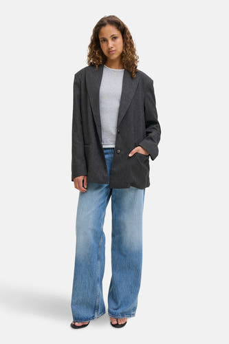 Blazer gris de JJXX, porté avec un chemisier gris et des jeans larges.
