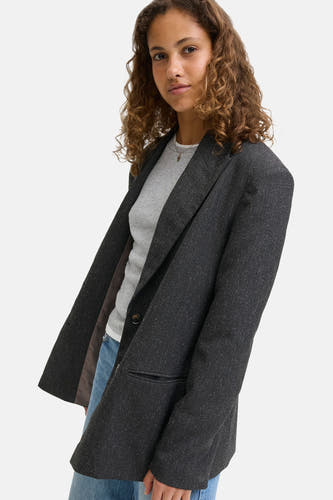 Blazer gris de JJXX avec une finition texturée, associé à un chemisier gris et des jeans bleus.