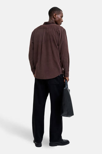 Gilet en velours côtelé marron avec longues manches de PREMIUM BLUE par JACK & JONES, vu de derrière, associé à un pantalon noir et une sac noir.