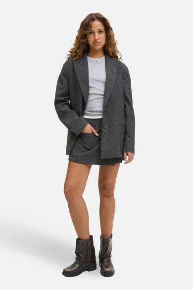 Short gris de JJXX, combiné avec un haut gris, une veste gris et des bottes brunes.
