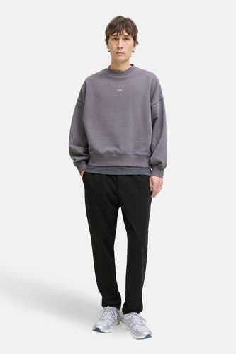 Pantalon noir de JACK & JONES JEANS INTELLIGENCE, combiné avec un pull gris et des baskets blanches.